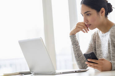 Hispanische Frau mit Mobiltelefon und Laptop - BLEF08862