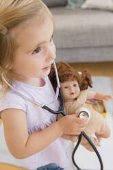 Caucasian girl playing doctor with doll - BLEF08897