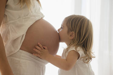Kaukasisches Mädchen küsst den Bauch der schwangeren Mutter - BLEF08905
