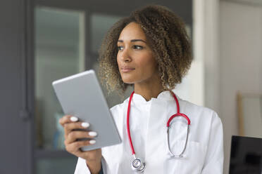 Portrait of young doctor with stethoscope and digital tablet looking at distance - MOEF02320
