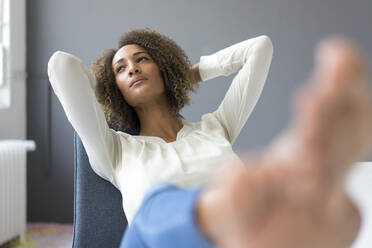 Portrait of young woman relaxing with feet up on desk - MOEF02340