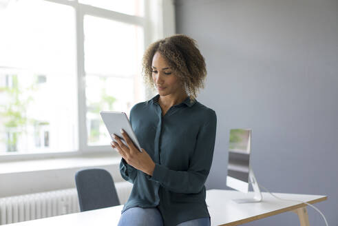 Junge Geschäftsfrau benutzt digitales Tablet im Büro - MOEF02364