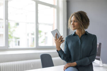 Smiling oung businesswoman with digital tablet in office - MOEF02366