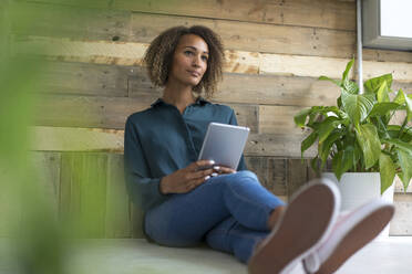 Portrait of pensive young woman with digital tablet - MOEF02371