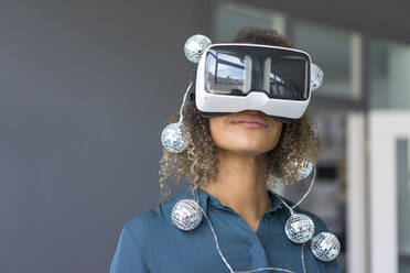 Smiling young woman with chain of lights using Virtual Reality Glasses - MOEF02379