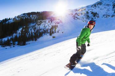 Gemischtrassiger Teenager beim Snowboarden - BLEF08930