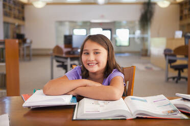 Lächelndes gemischtrassiges Mädchen studiert in der Bibliothek - BLEF08942