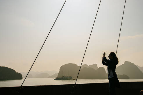 Kaukasische Frau beim Fotografieren von Felsformationen in der Ha Long Bay, Vietnam - BLEF09023