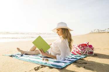 Caucasian woman reading book on beach - BLEF09077