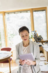 Businesswoman using digital tablet in office - BLEF09120