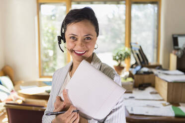 Businesswoman using notepad and headset in office - BLEF09121