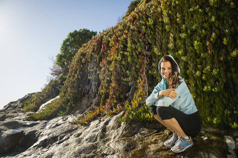 Mixed race woman smiling on rocky beach stock photo