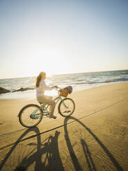 Mixed race woman riding bicycle on beach - BLEF09133