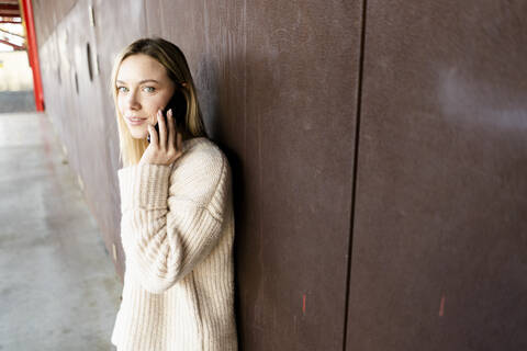 Porträt einer jungen blonden Frau beim Telefonieren im Freien, lizenzfreies Stockfoto
