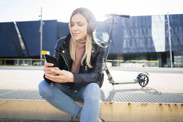 Porträt einer jungen Frau, die mit Smartphone und Kopfhörern Musik hört, Barcelona, Spanien - GIOF06613