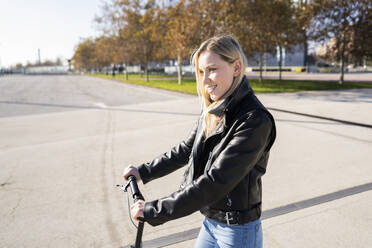 Smiling young woman with kick sccoter - GIOF06619