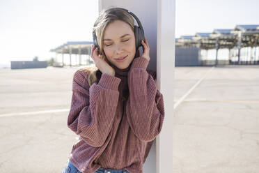 Portrait of smiling young woman listening music with wireless headphones, Barcelona, Spain - GIOF06625