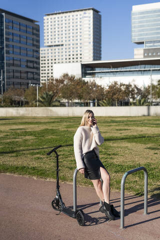 Junge Frau mit Kick-Scooter und Smartphone, lizenzfreies Stockfoto