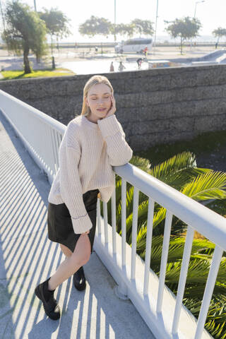 Porträt einer blonden jungen Frau, die sich auf einem Steg ausruht, lizenzfreies Stockfoto