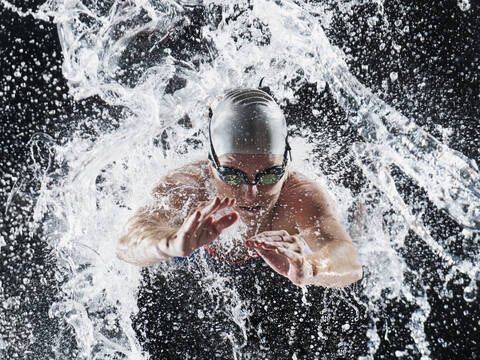 Kaukasischer Schwimmer beim Planschen im Wasser, lizenzfreies Stockfoto