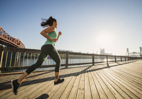 Caucasian woman jogging on urban waterfront stock photo