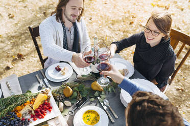 Kaukasische Freunde stoßen mit Wein an einem Tisch im Freien an - BLEF09309