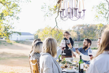 Friends toasting with wine at outdoor table - BLEF09315