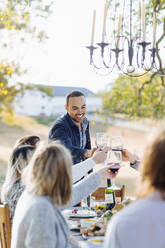 Friends toasting with wine at outdoor table - BLEF09318