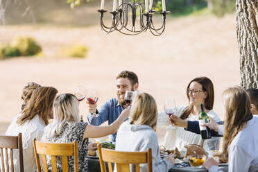 Friends toasting with wine at outdoor table - BLEF09334