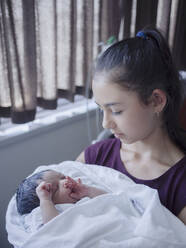 Close up of girl holding newborn baby brother - BLEF09340
