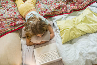 Kaukasisches Mädchen mit Laptop auf dem Bett - BLEF09445