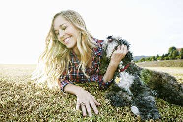 Caucasian woman petting dog in park - BLEF09455