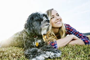 Caucasian woman and dog laying in park - BLEF09456