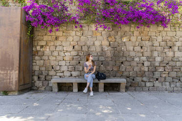 Woman with backpack and cell phone waiting on a bench - AFVF03566