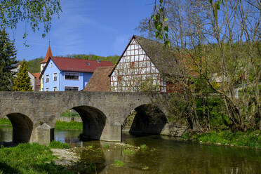 Alte Bogenbrücke über die Tauber mit Stadthäusern im Hintergrund, Adelshofen, Bayern, Deutschland - LBF02617