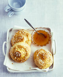 Overhead view of homemade bread rolls with jam on tray - PPXF00198