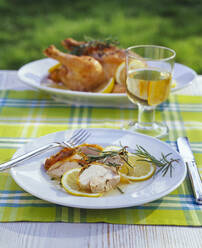 Gebratenes Huhn in Zitronensauce und ein Glas Weißwein auf dem Gartentisch - PPXF00206
