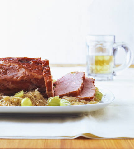 Kasseler mit Sauerkraut und Weintrauben bei Tisch, lizenzfreies Stockfoto