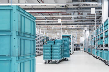 Turquoise colored containers inside modern factory warehouse, Stuttgart, Germany - DIGF07165