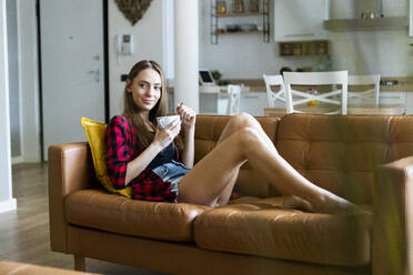 Relaxed young woman eating cereals in living room at home - GIOF06664