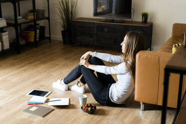 Entspannte junge Frau, die zu Hause auf dem Boden sitzt und eine Pause macht - GIOF06717