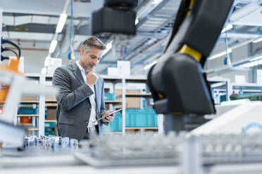 Businessman with tablet in a modern factory hall - DIGF07214