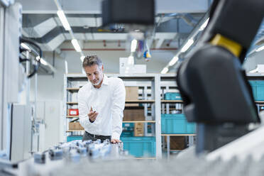 Businessman in a modern factory holding workpiece - DIGF07216