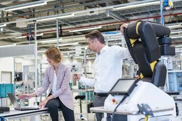 Businessman and businesswoman talking in a modern factory hall - DIGF07232