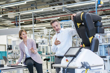 Businessman and businesswoman talking in a modern factory hall - DIGF07234