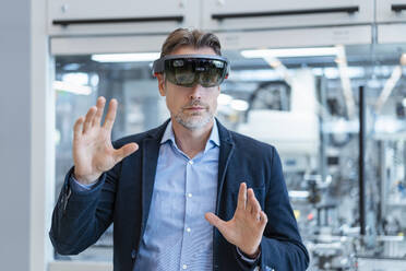 Businessman wearing AR glasses in a modern factory - DIGF07236