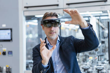Businessman wearing AR glasses in a modern factory - DIGF07239