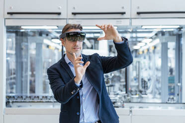 Businessman wearing AR glasses in a modern factory - DIGF07240