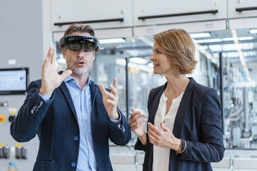 Businessman with AR glasses and businesswoman in a modern factory - DIGF07242