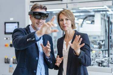 Businessman with AR glasses and businesswoman in a modern factory - DIGF07243